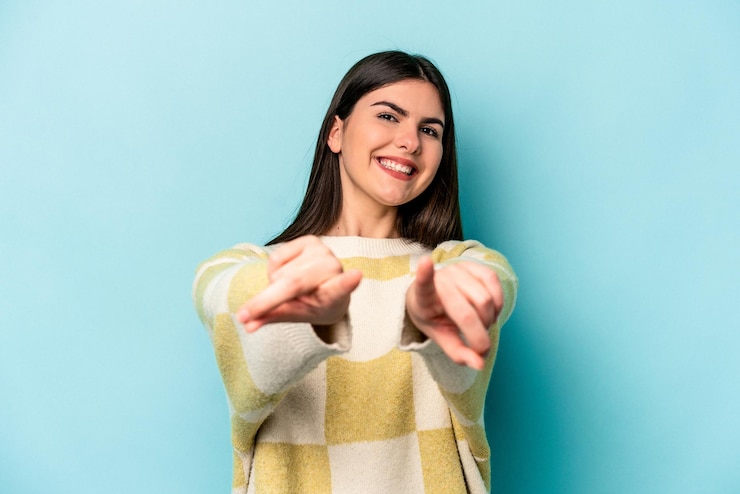 Photo young caucasian woman isolated on blue background pointing to front with fingers