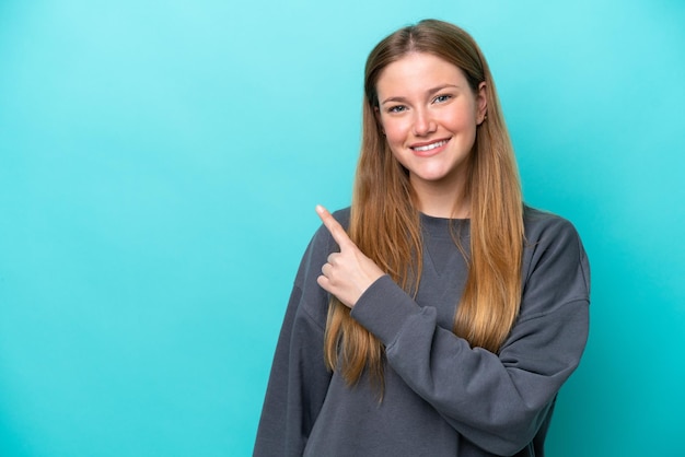 Young caucasian woman isolated on blue background pointing to the side to present a product