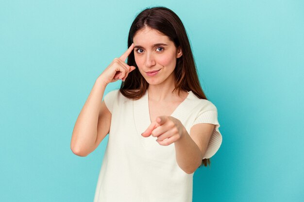 Young caucasian woman isolated on blue background pointing temple with finger, thinking, focused on a task.