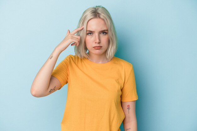 Young caucasian woman isolated on blue background pointing temple with finger, thinking, focused on a task.