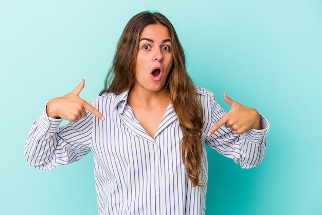 Young caucasian woman isolated on blue background  points down with fingers, positive feeling.