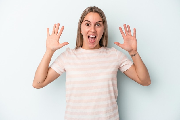 Young caucasian woman isolated on blue background receiving a pleasant surprise, excited and raising hands.