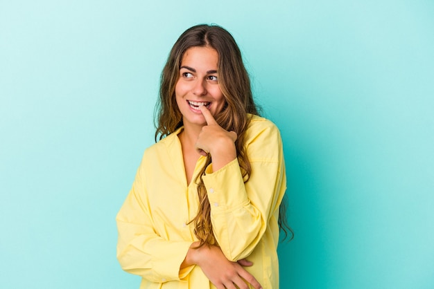 Young caucasian woman isolated on blue background  relaxed thinking about something looking at a copy space.