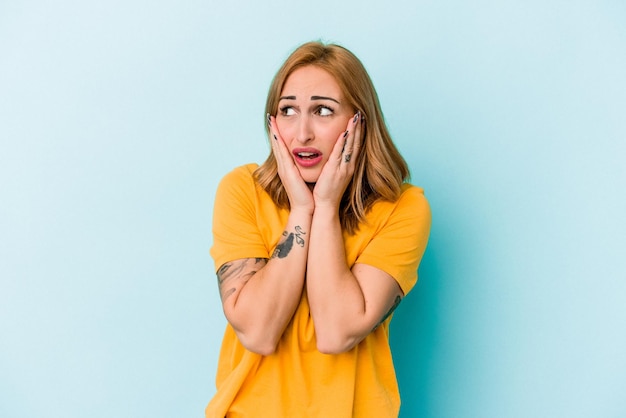 Young caucasian woman isolated on blue background scared and afraid.