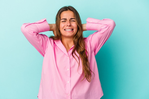 Young caucasian woman isolated on blue background  screaming with rage.