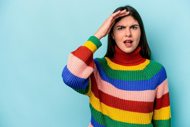 Young caucasian woman isolated on blue background shouts loud keeps eyes opened and hands tense