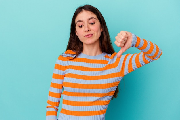 Young caucasian woman isolated on blue background showing a dislike gesture, thumbs down. Disagreement concept.