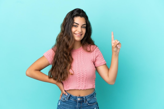 Foto giovane donna caucasica isolata su sfondo blu che mostra e alza un dito in segno di meglio