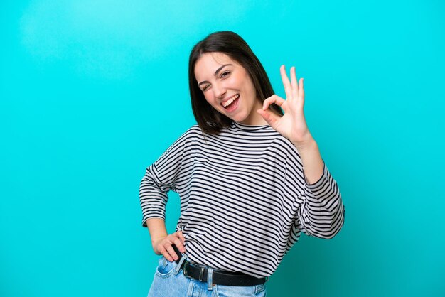 Young caucasian woman isolated on blue background showing ok sign with fingers