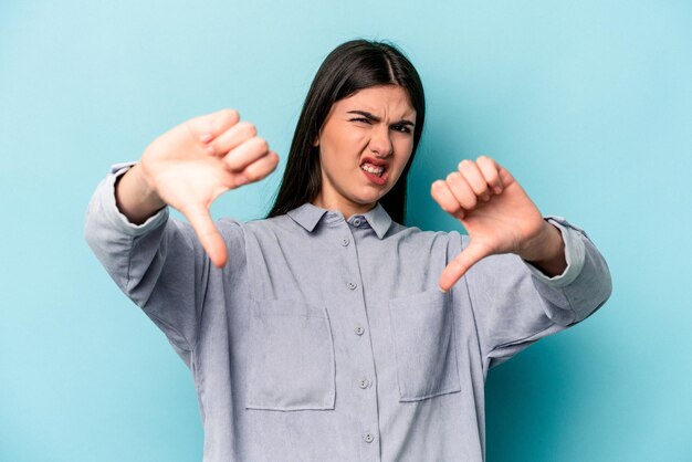 Young caucasian woman isolated on blue background showing thumb down and expressing dislike