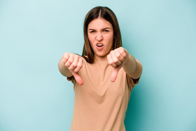 Young caucasian woman isolated on blue background showing thumb down and expressing dislike