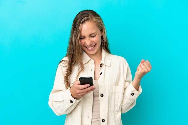 Young caucasian woman isolated on blue background surprised and sending a message