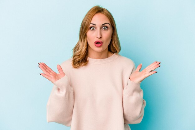 Young caucasian woman isolated on blue background surprised and shocked.