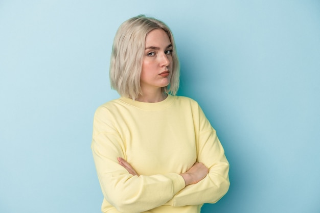 Young caucasian woman isolated on blue background suspicious, uncertain, examining you.