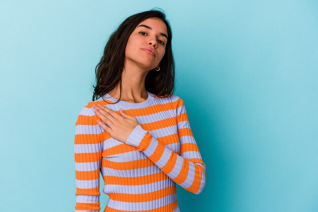 Young caucasian woman isolated on blue background taking an oath, putting hand on chest.