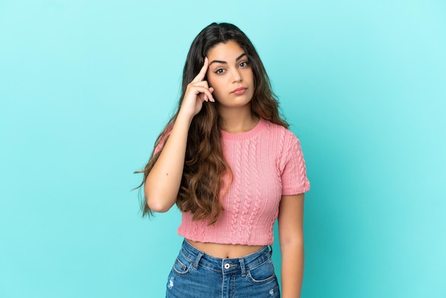 Young caucasian woman isolated on blue background thinking an idea