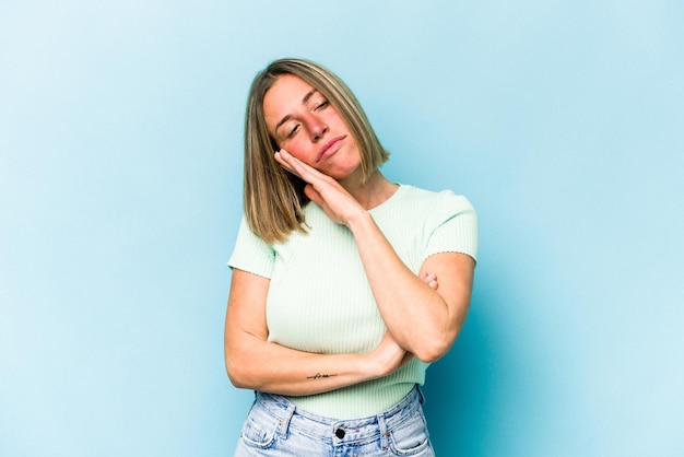 Young caucasian woman isolated on blue background tired of a repetitive task