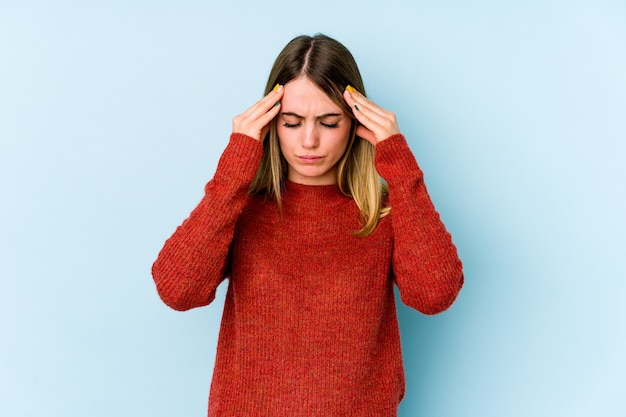 Young caucasian woman isolated on blue background touching temples and having headache.