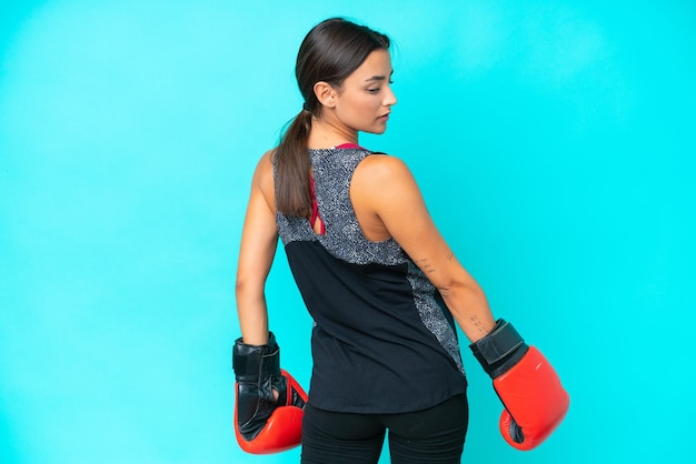 Young caucasian woman isolated on blue background with boxing gloves