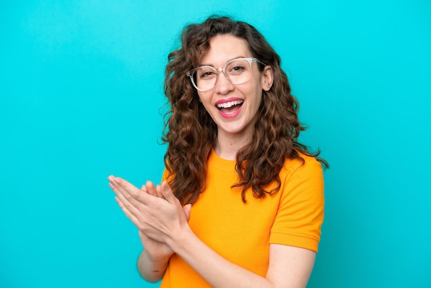 Young caucasian woman isolated on blue background With glasses and applauding