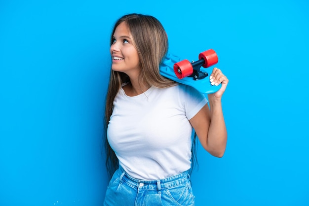 Young caucasian woman isolated on blue background with a skate with happy expression