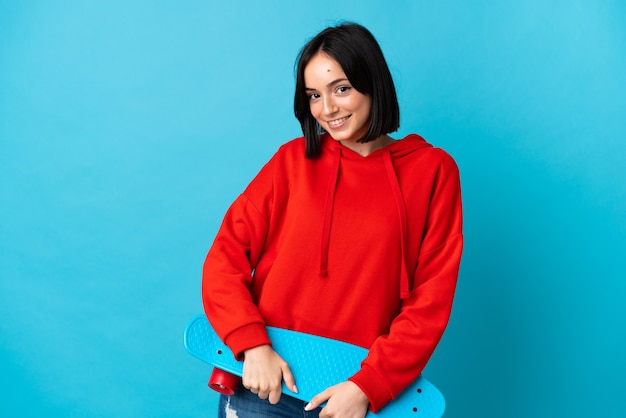 Young caucasian woman isolated on blue background with a skate