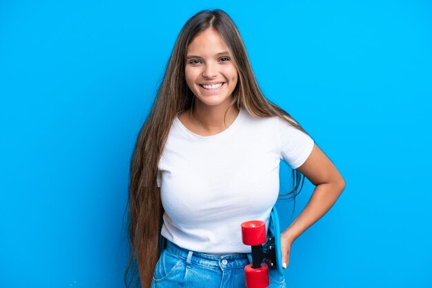 Young caucasian woman isolated on blue background with a skate