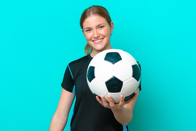Young caucasian woman isolated on blue background with soccer ball