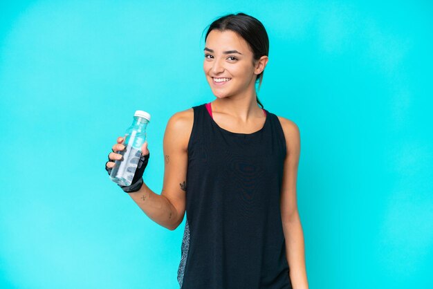 Young caucasian woman isolated on blue background with sports water bottle