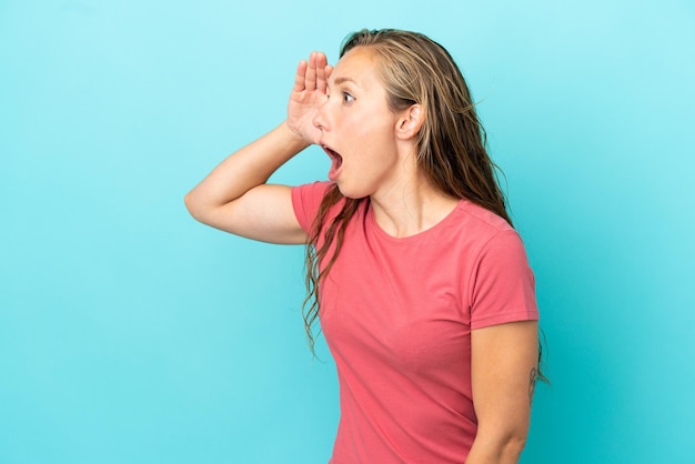 Young caucasian woman isolated on blue background with surprise expression while looking side