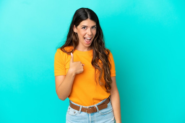 Young caucasian woman isolated on blue background with surprise facial expression