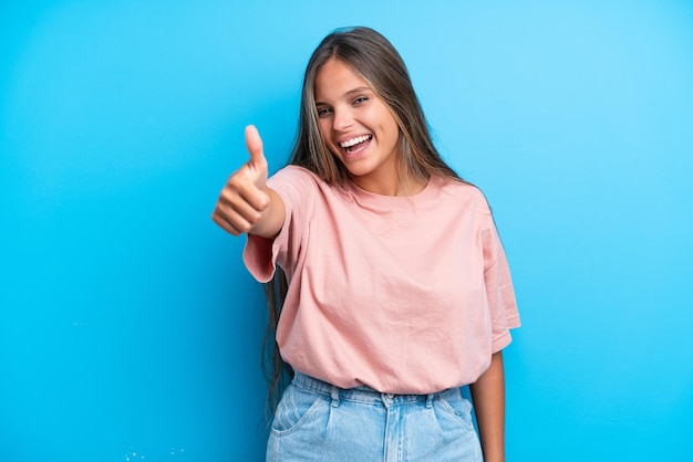 Young caucasian woman isolated on blue background with thumbs up because something good has happened