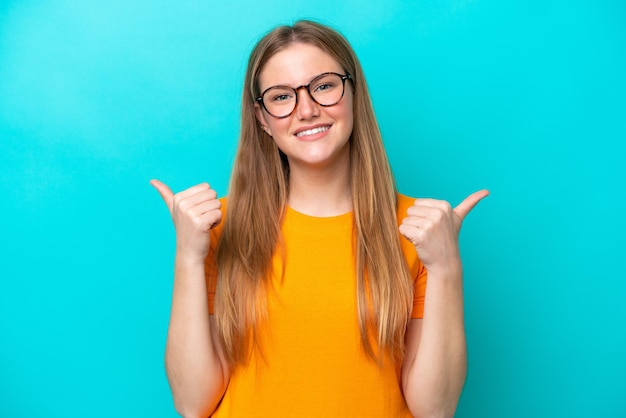 Young caucasian woman isolated on blue background with thumbs up gesture and smiling