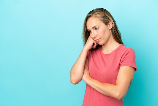 Young caucasian woman isolated on blue background with tired and bored expression