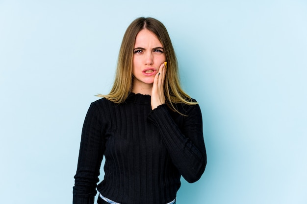 Young caucasian woman isolated on blue wall having a strong teeth pain, molar ache.