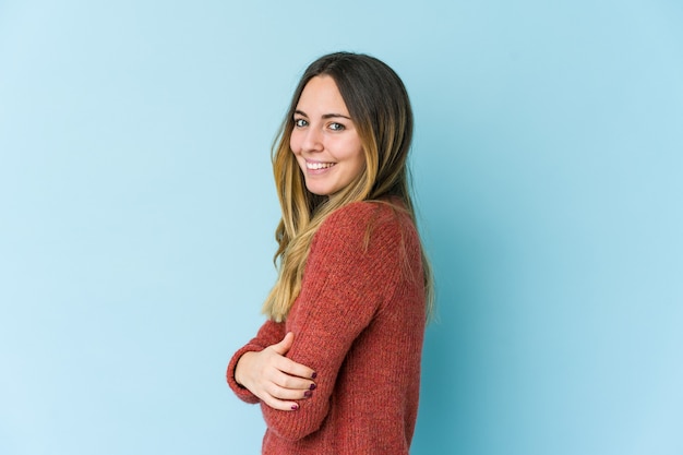 Young caucasian woman isolated on blue wall laughing and having fun.