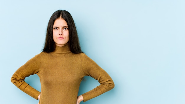 Young caucasian woman isolated on blue wall sad, serious face, feeling miserable and displeased.