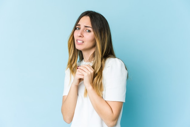 Young caucasian woman isolated on blue wall scared and afraid.