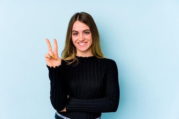 Young caucasian woman isolated on blue wall showing number two with fingers.