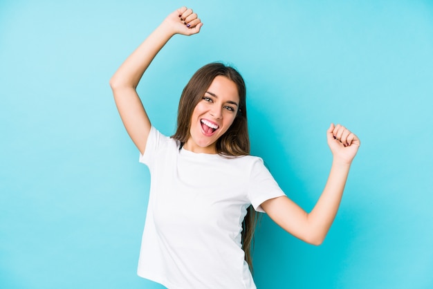 Young caucasian woman  isolated celebrating a special day, jumps and raise arms with energy.