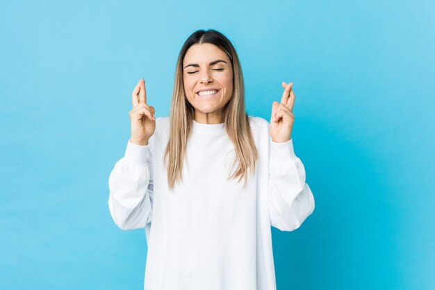 Young caucasian woman isolated crossing fingers for having luck