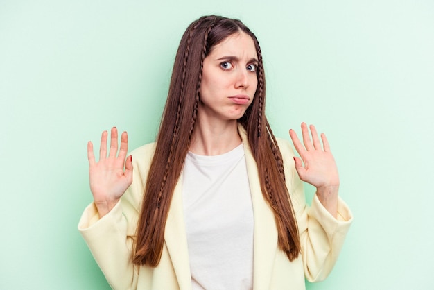 Photo young caucasian woman isolated on green background being shocked due to an imminent danger