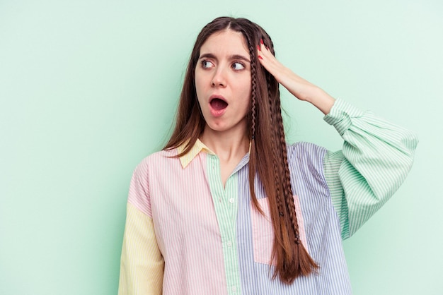 Young caucasian woman isolated on green background being shocked, she has remembered important meeting.