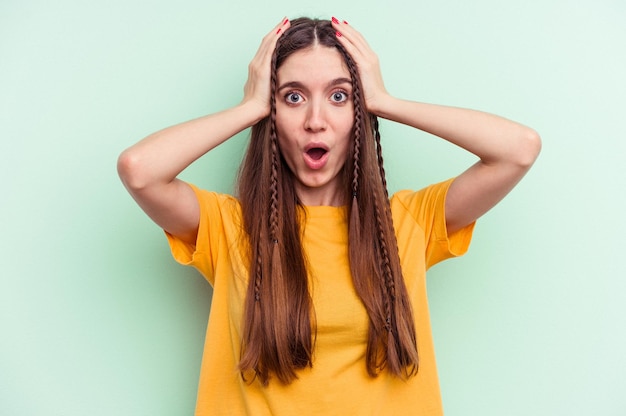 Young caucasian woman isolated on green background being shocked, she has remembered important meeting.