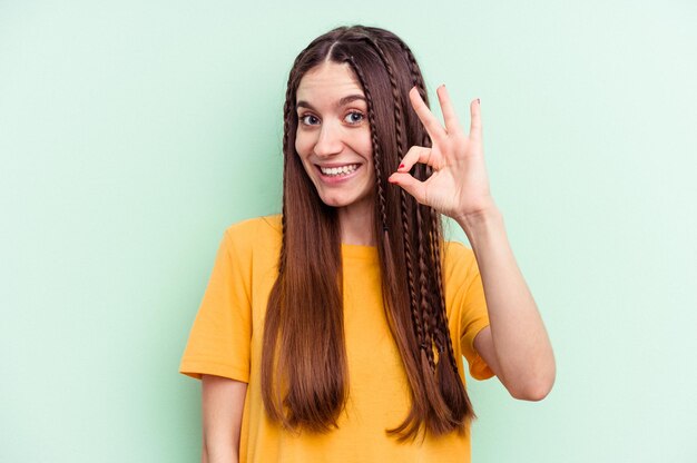 Young caucasian woman isolated on green background cheerful and confident showing ok gesture