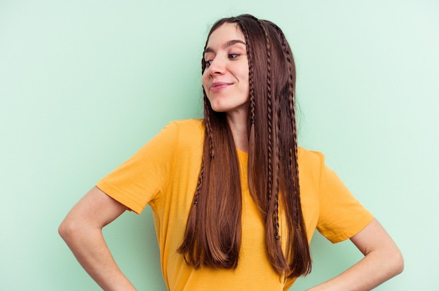 Young caucasian woman isolated on green background dreaming of achieving goals and purposes