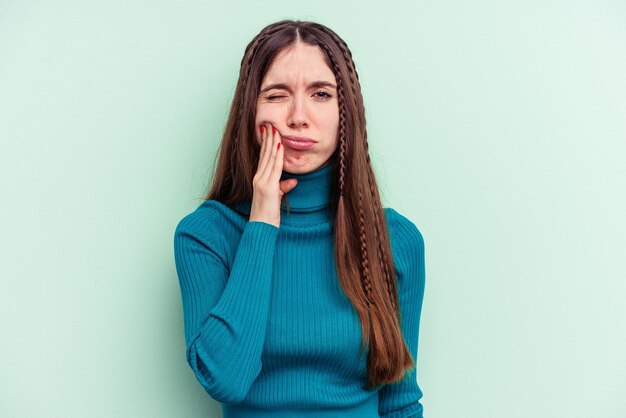 Photo young caucasian woman isolated on green background having a strong teeth pain molar ache