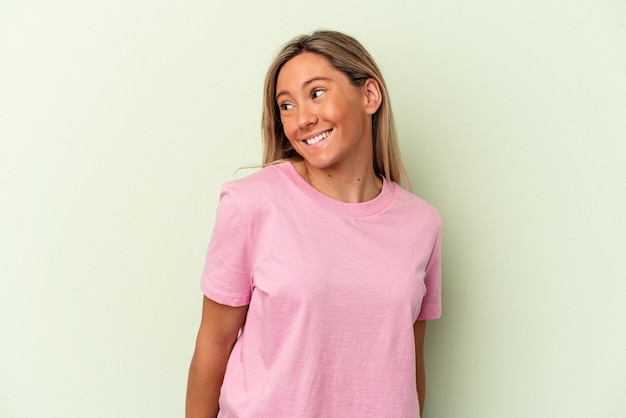 Photo young caucasian woman isolated on green background laughs and closes eyes, feels relaxed and happy.