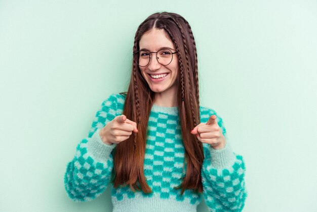 Young caucasian woman isolated on green background pointing to front with fingers.