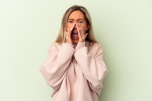 Young caucasian woman isolated on green background shouting excited to front.